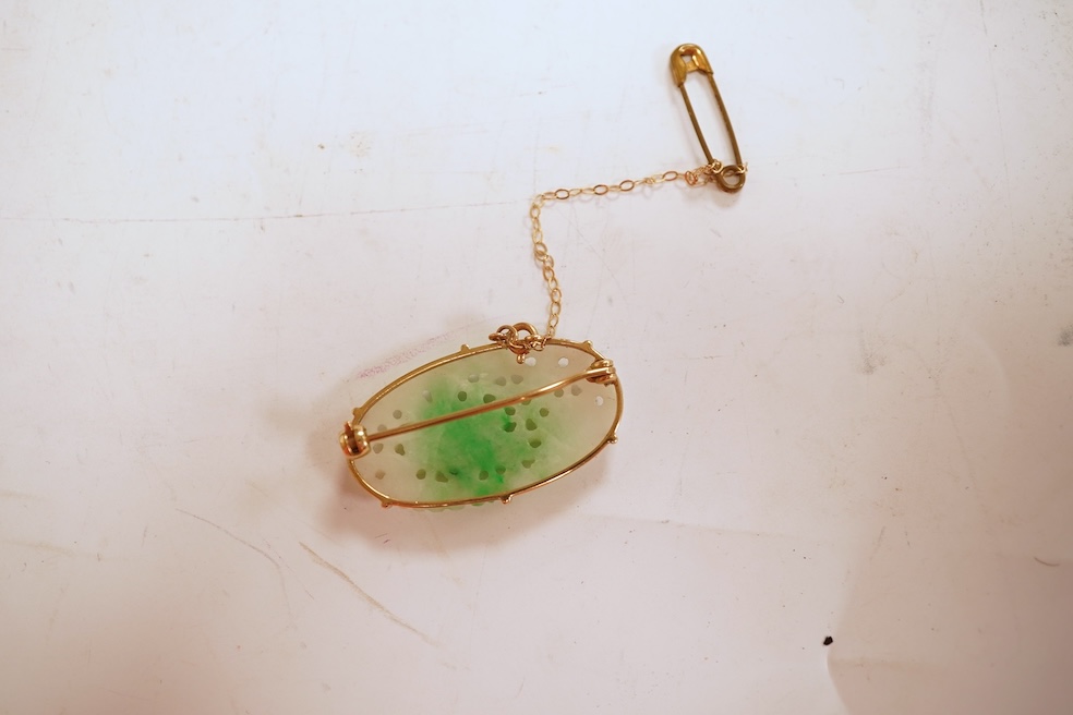 A jadeite brooch, set with an oval jadeite of mottled green and white, carved to depict flowers, mounted in 9ct gold, length 3.2cm, British hallmarks, maker's mark for Cropp & Farr, gross weight approximately 4.5 grams,